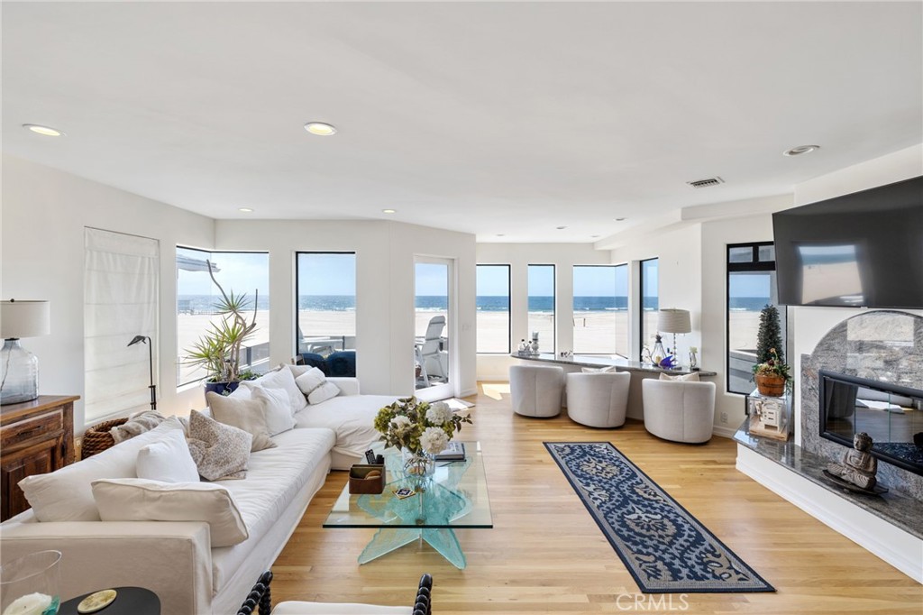 Furnished living room with a white sectional and stone fireplace overlooking the ocean.