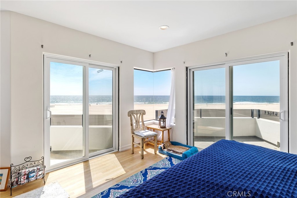 Bedroom with blue quilt and sliding glass doors overlooking the beach and ocean.