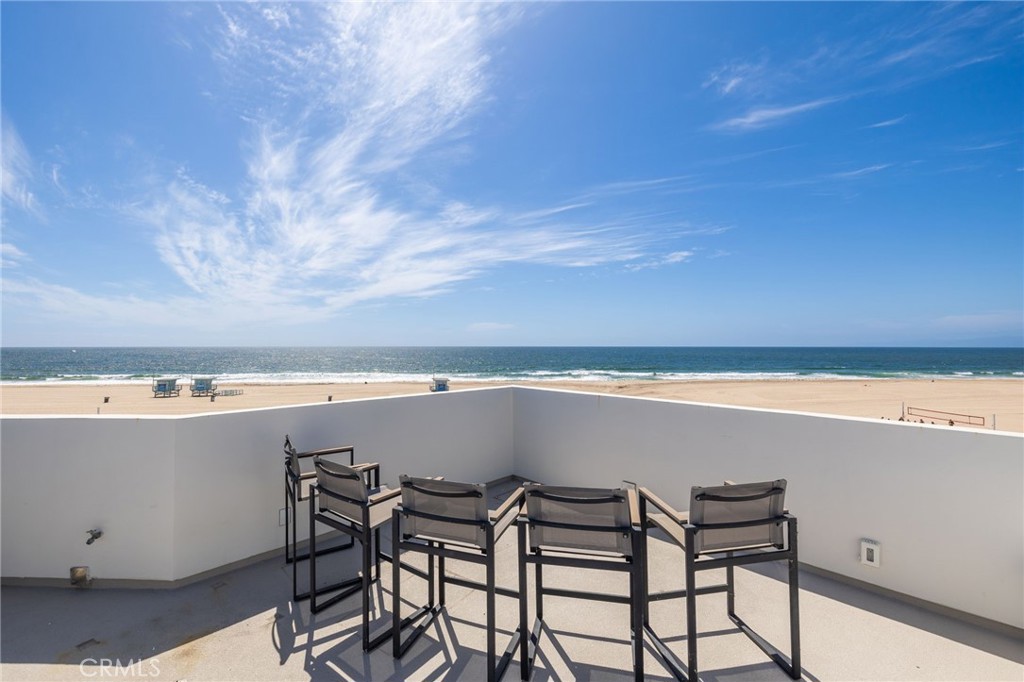 Rooftop terrace with chairs overlooking the sandy beach and ocean.