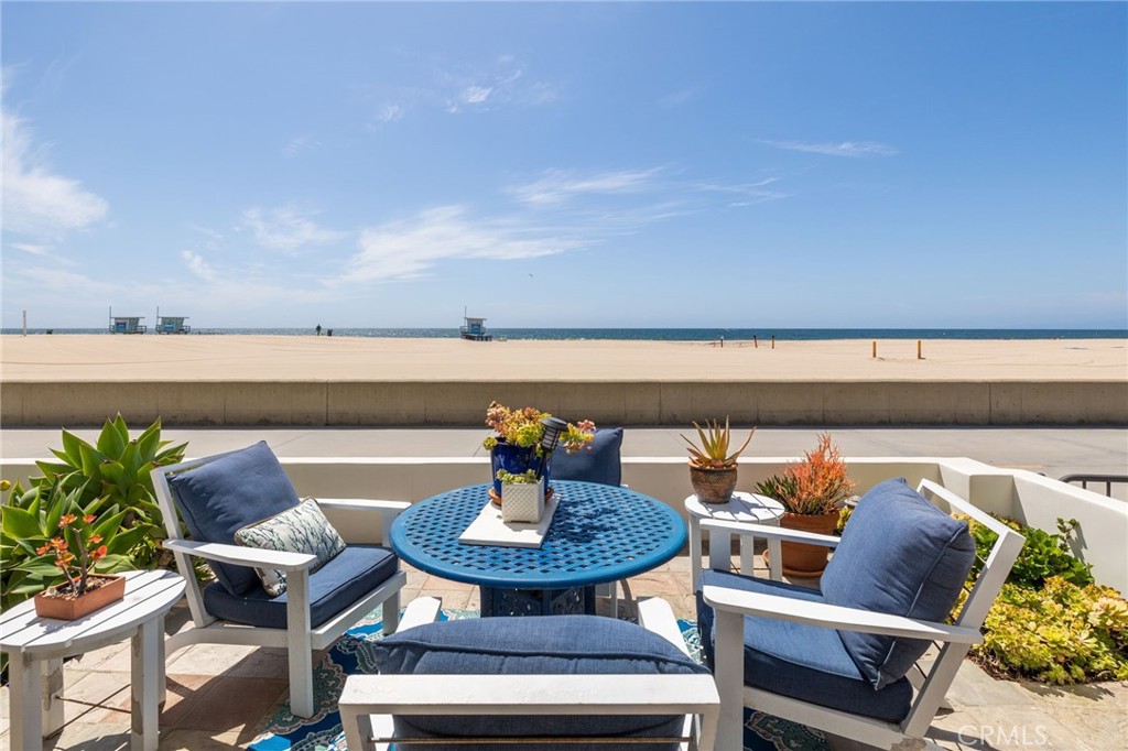 Beachfront patio with blue seating overlooks the sandy beach and ocean.