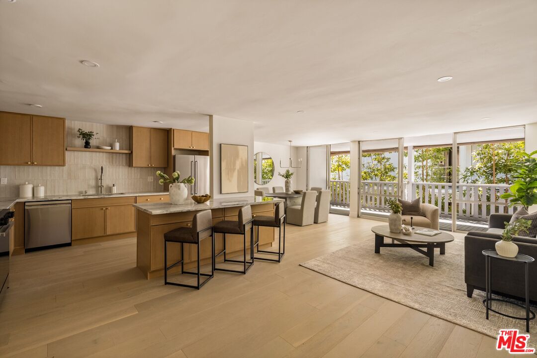 Open-plan condo kitchen and living room with a wood island, large windows, and balcony access.