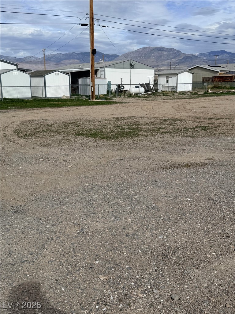 Metal utility buildings behind a gravel lot, with mountains in the distance.