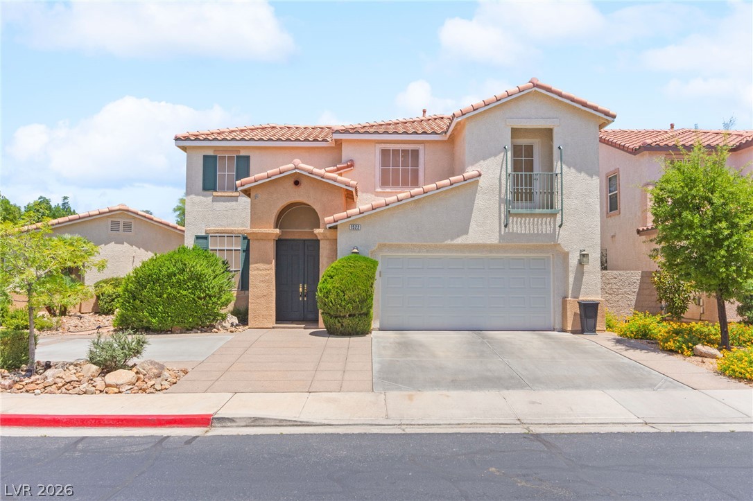 Two-story stucco home with a tile roof, arched entry, balcony, and two-car garage.