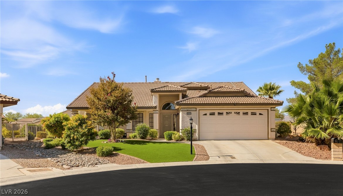 Single-story stucco home with a tile roof, two-car garage, and landscaped front yard.