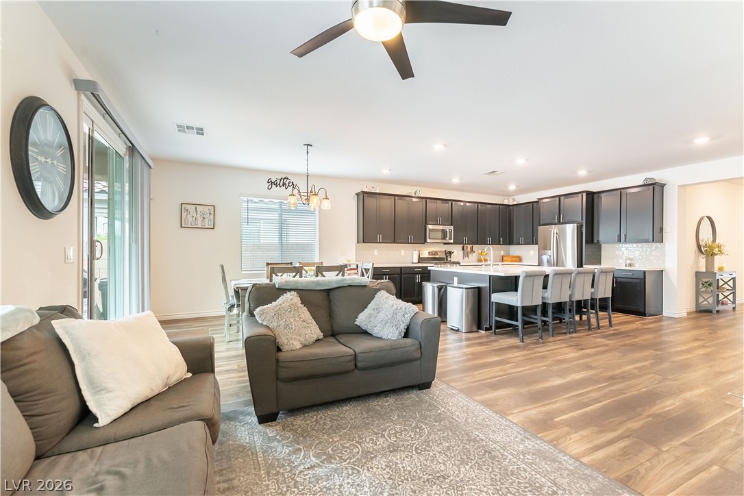 Open-plan living room and kitchen with dark cabinets, a large island, and wood floors.