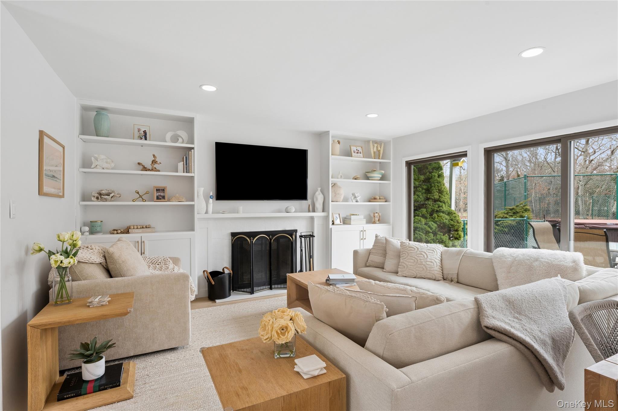 Furnished living room with a cream sectional, built-in shelves, fireplace, and sliding glass doors to a patio.