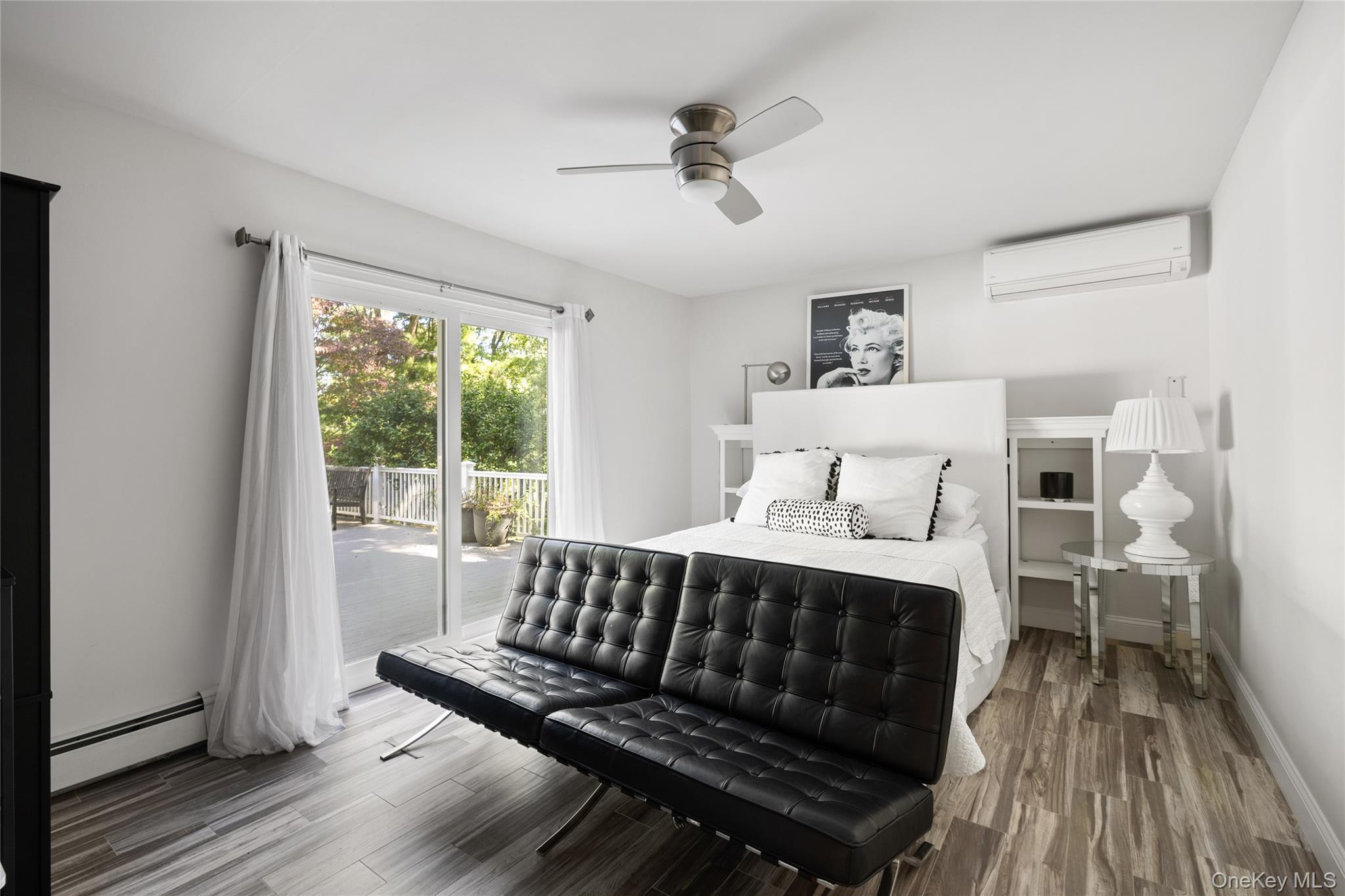 Furnished bedroom with a black tufted sofa and sliding doors opening onto a deck.