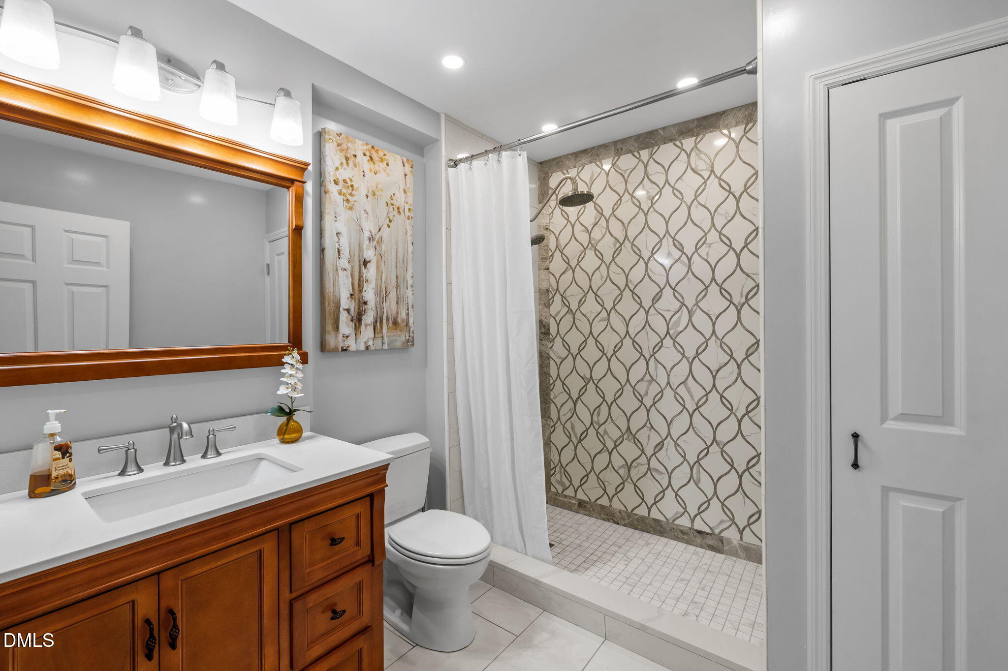 Bathroom with a wood vanity, large mirror, and walk-in shower with patterned tile.
