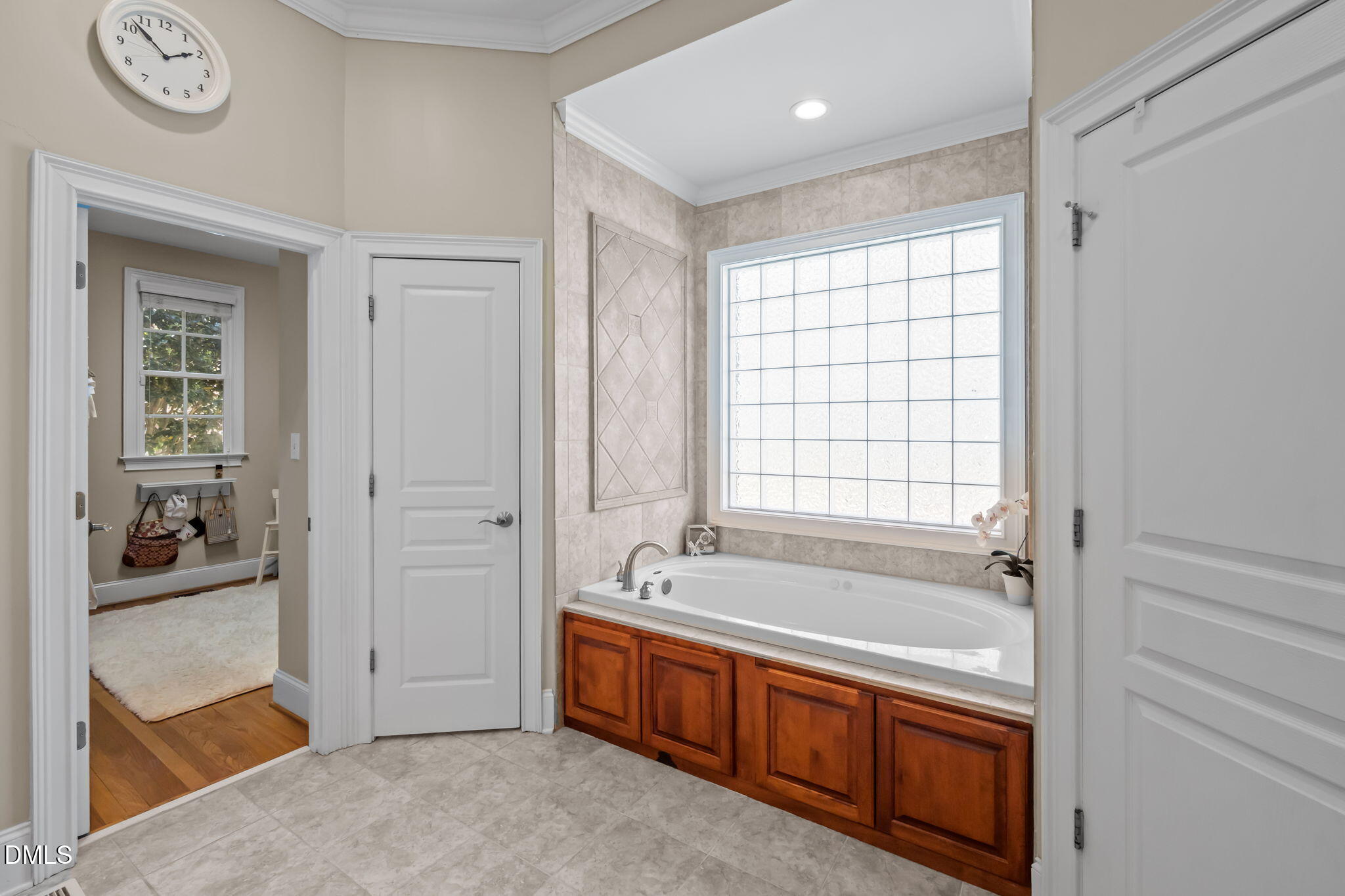 Bathroom with a built-in tub, warm wood cabinetry, beige tile, and a large window.