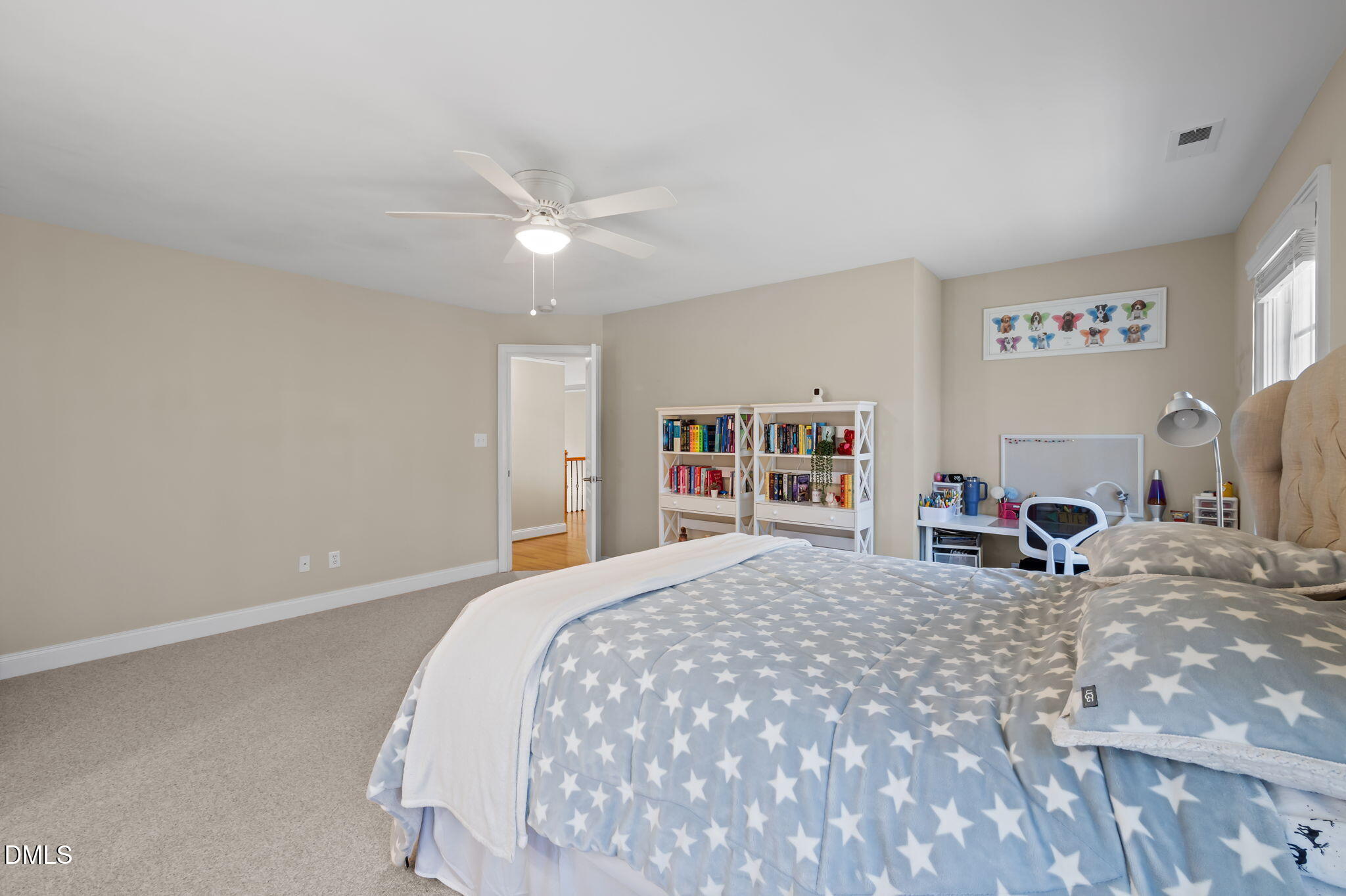 Bedroom with a star-patterned bedspread, bookshelves, and a study desk.