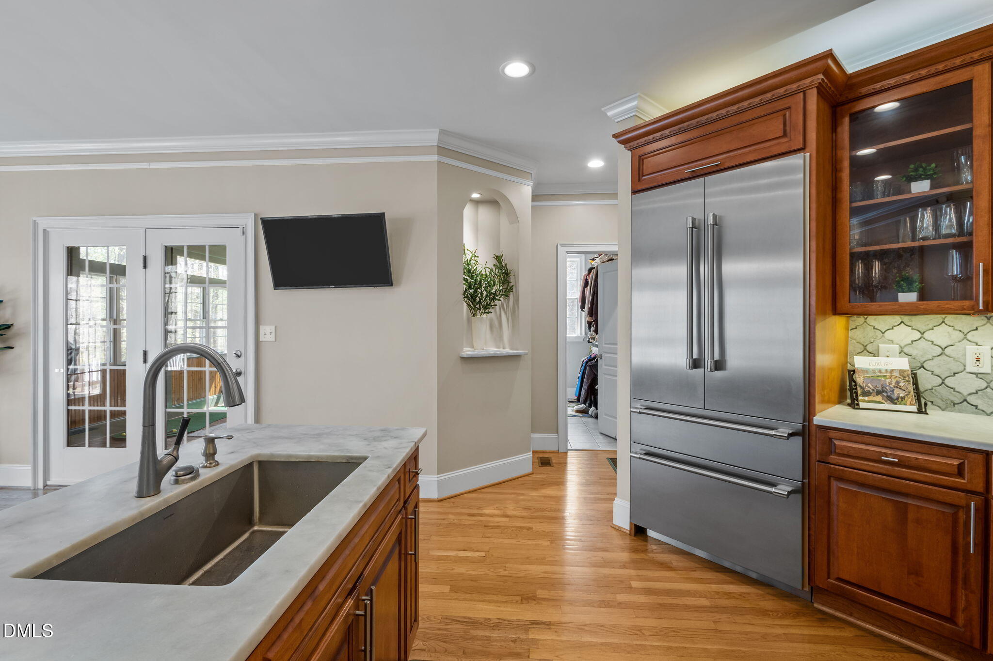 Kitchen with rich wood cabinetry, a stainless-steel refrigerator, and a large island sink.