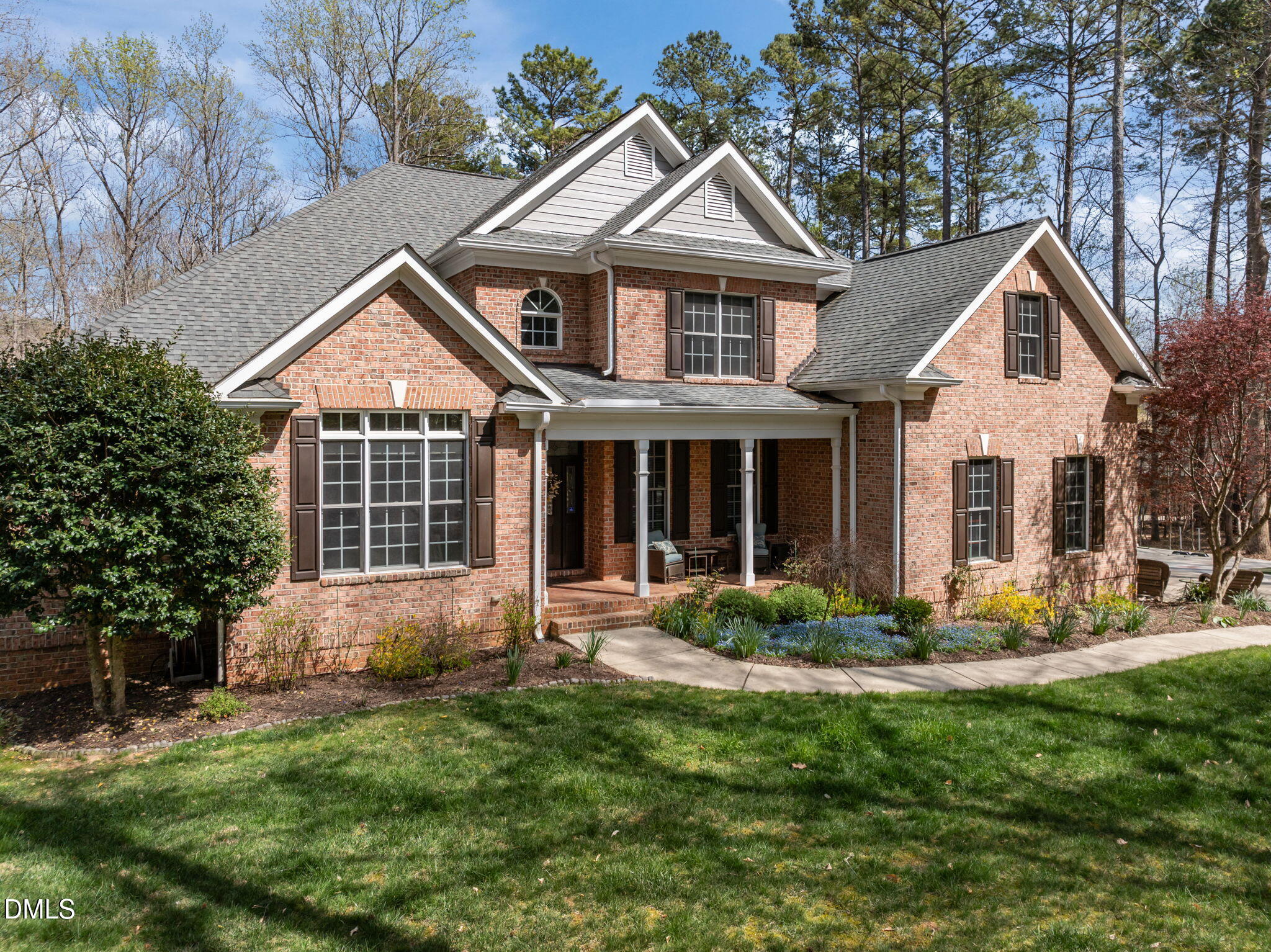 Two-story brick house with steep gables, a covered porch, and a landscaped front lawn.
