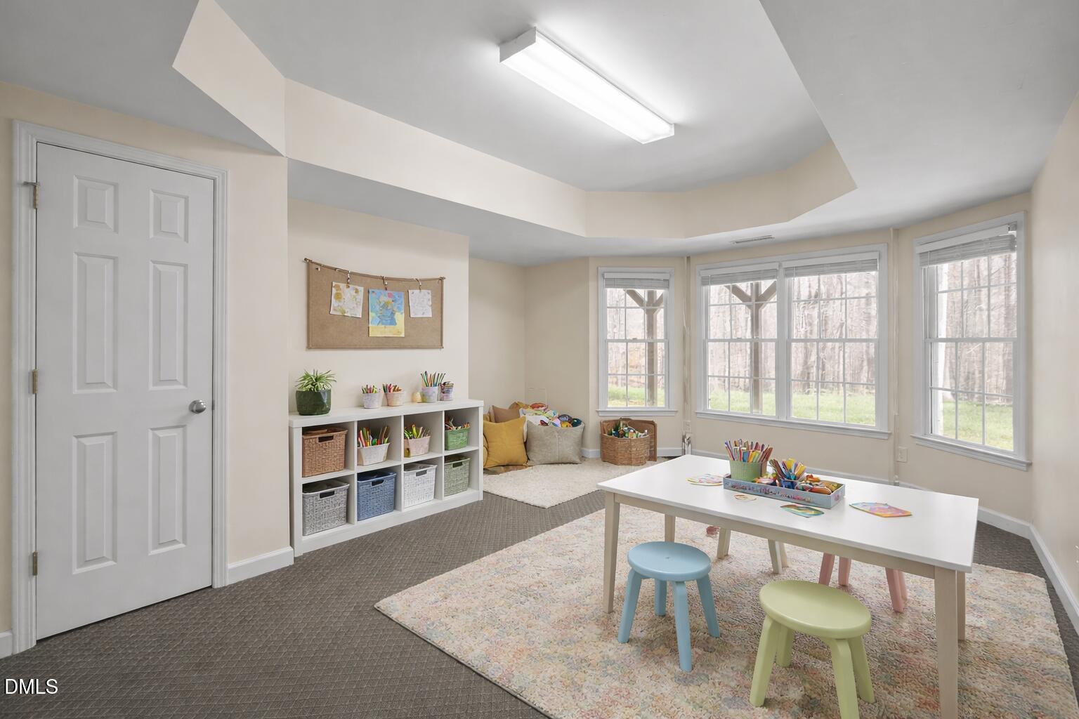 Playroom with a craft table, colorful stools, cubby storage, and large windows.