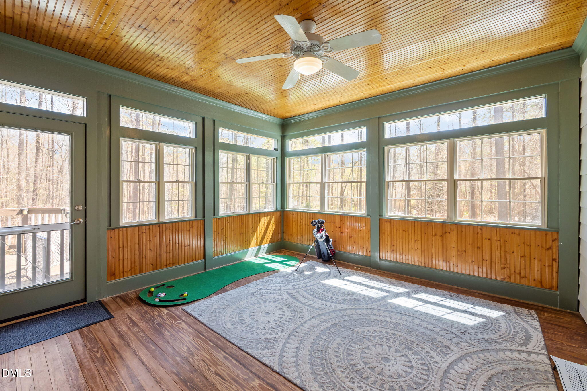 Sunroom with a wood-plank ceiling, expansive wooded views, and a small putting green.