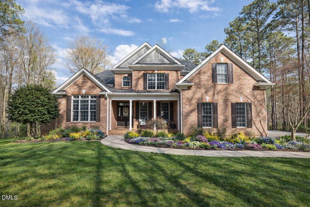 Brick home with a covered front porch, landscaped flower beds, and a curved walkway.