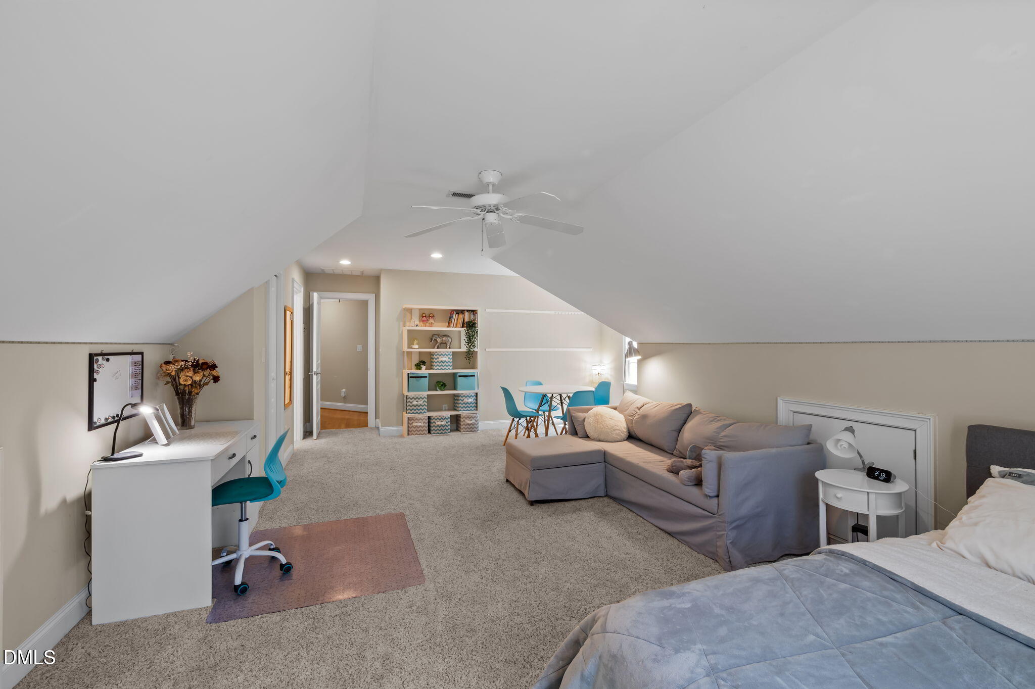 Furnished bedroom and sitting area with a gray sectional, desk, and sloped ceiling.