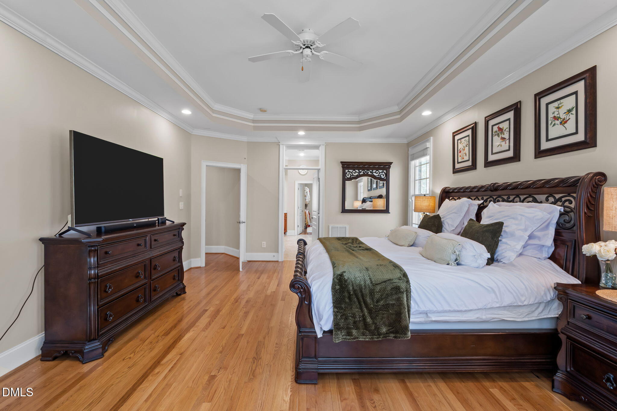 Bedroom with a dark wood bed, green throw, hardwood floors, and a tray ceiling.