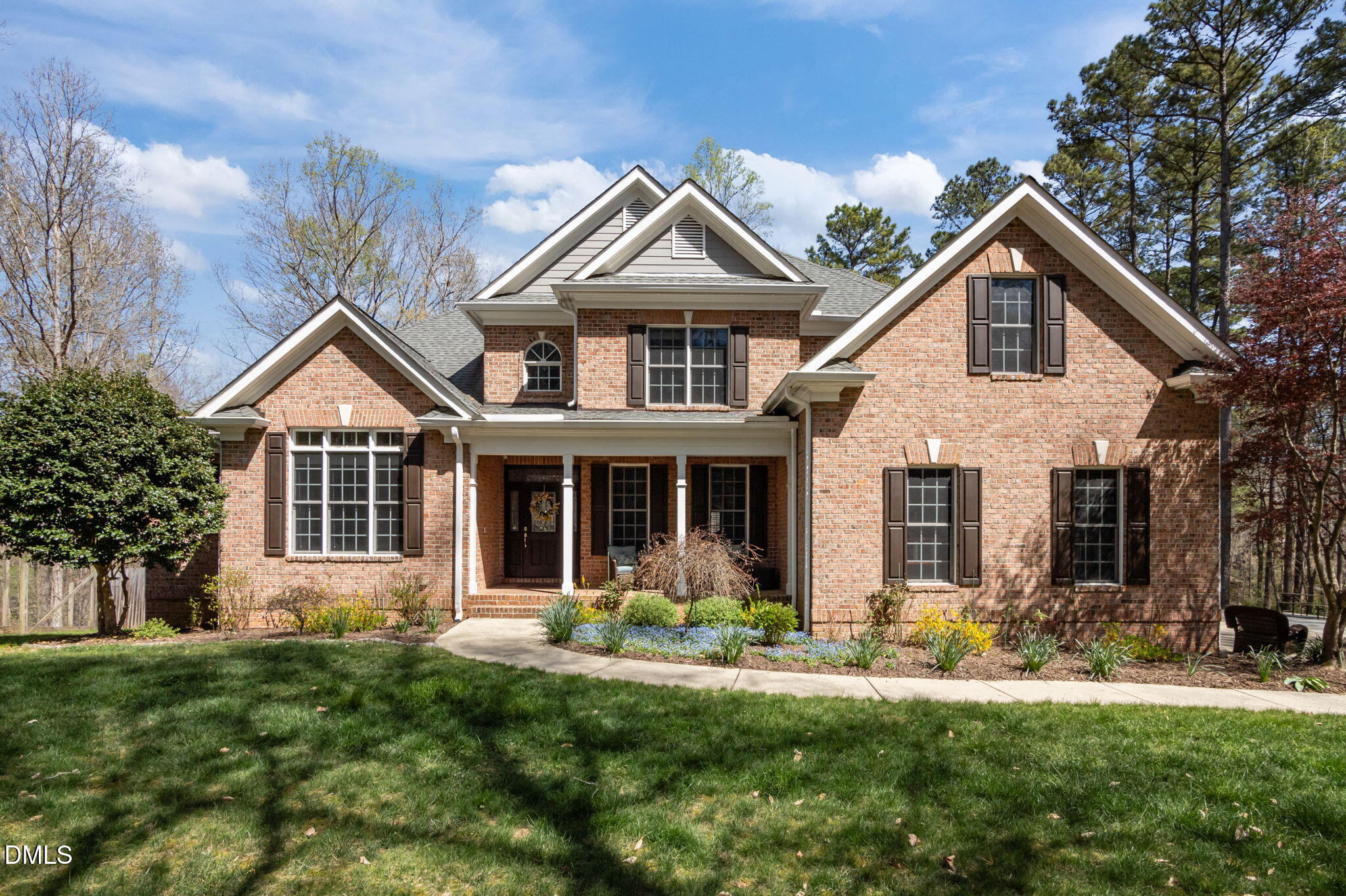 Two-story brick house with multiple gables, a covered porch, and landscaped front lawn.