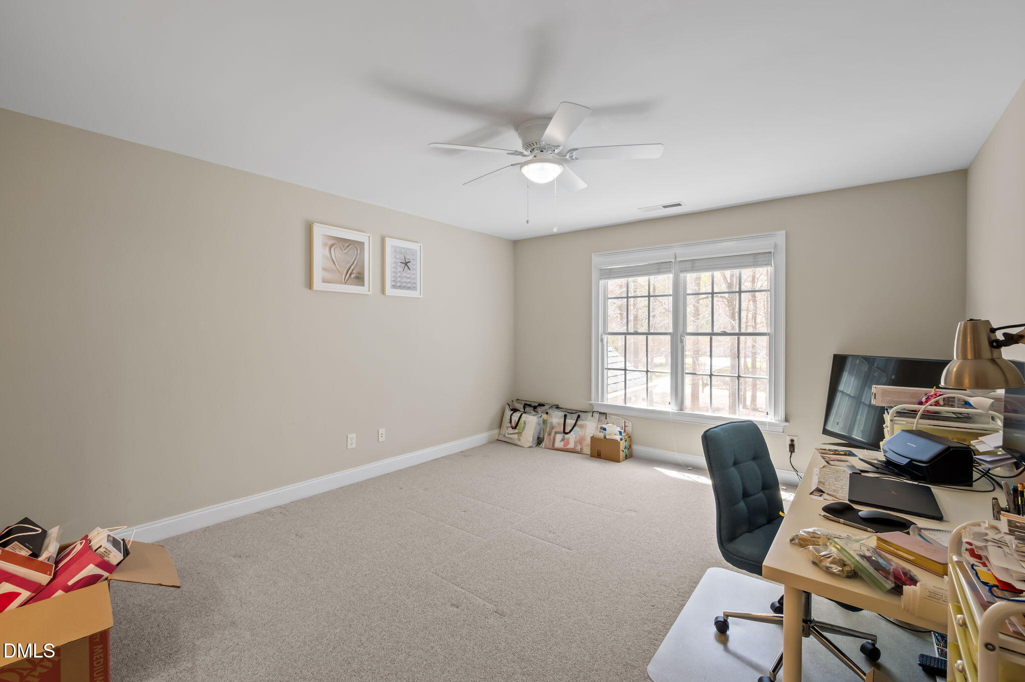 Home office with a cluttered desk, rolling chair, and large double window.