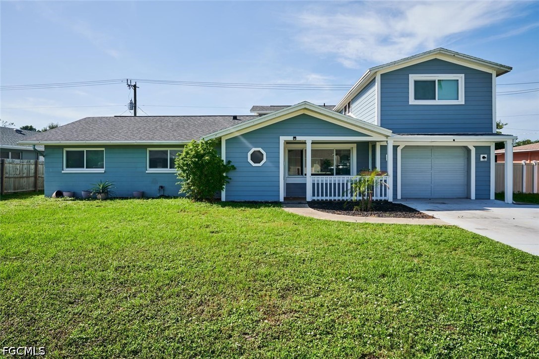Blue house with white trim, a covered porch, attached garage, and broad front lawn.