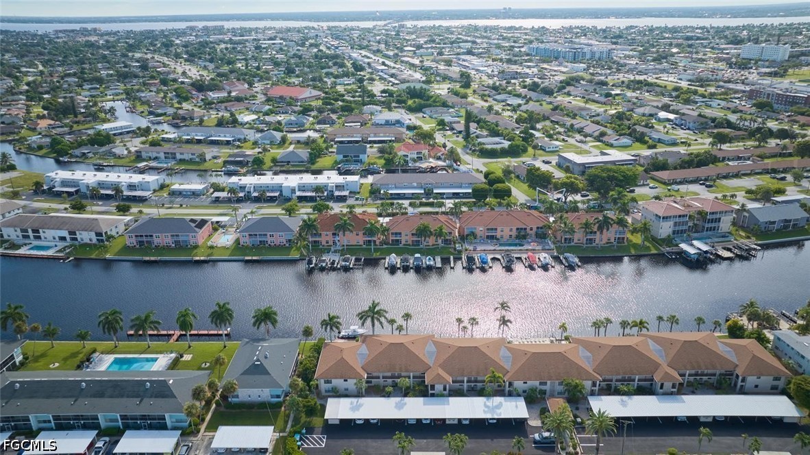 Waterfront condominium community along a canal with docks, boats, and a swimming pool.
