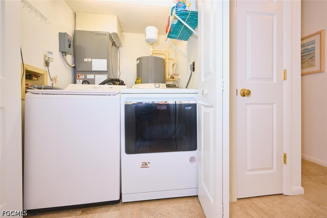 Laundry room with a top-loading washer, Maytag dryer, water heater, and utility equipment.