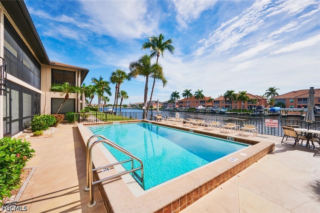 Outdoor pool beside a canal, with palm trees and lounge chairs along the water.