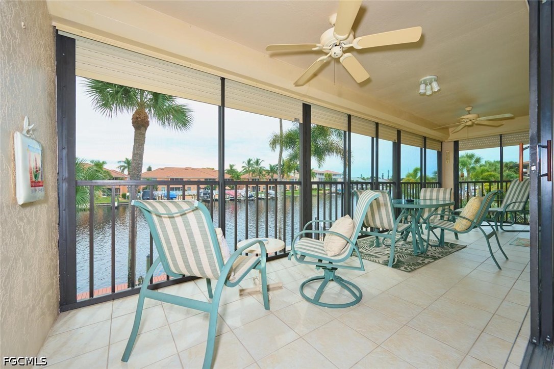 Covered lanai with striped chairs and ceiling fans overlooking a canal.