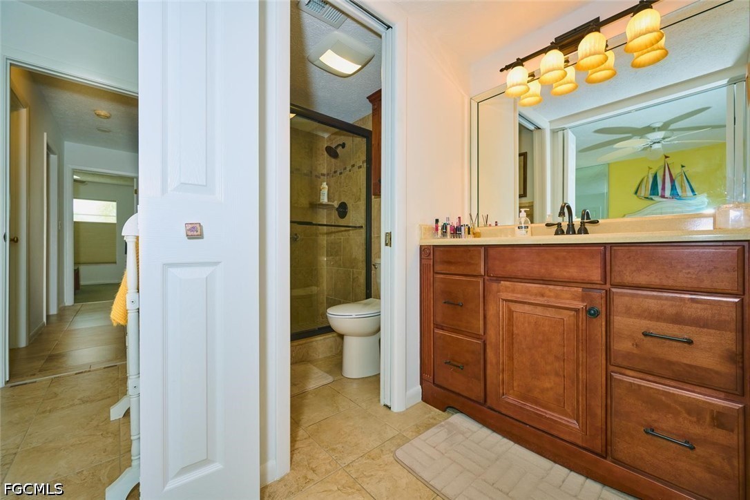 Bathroom with a wide wooden vanity, large mirror, and glass-enclosed tiled shower.