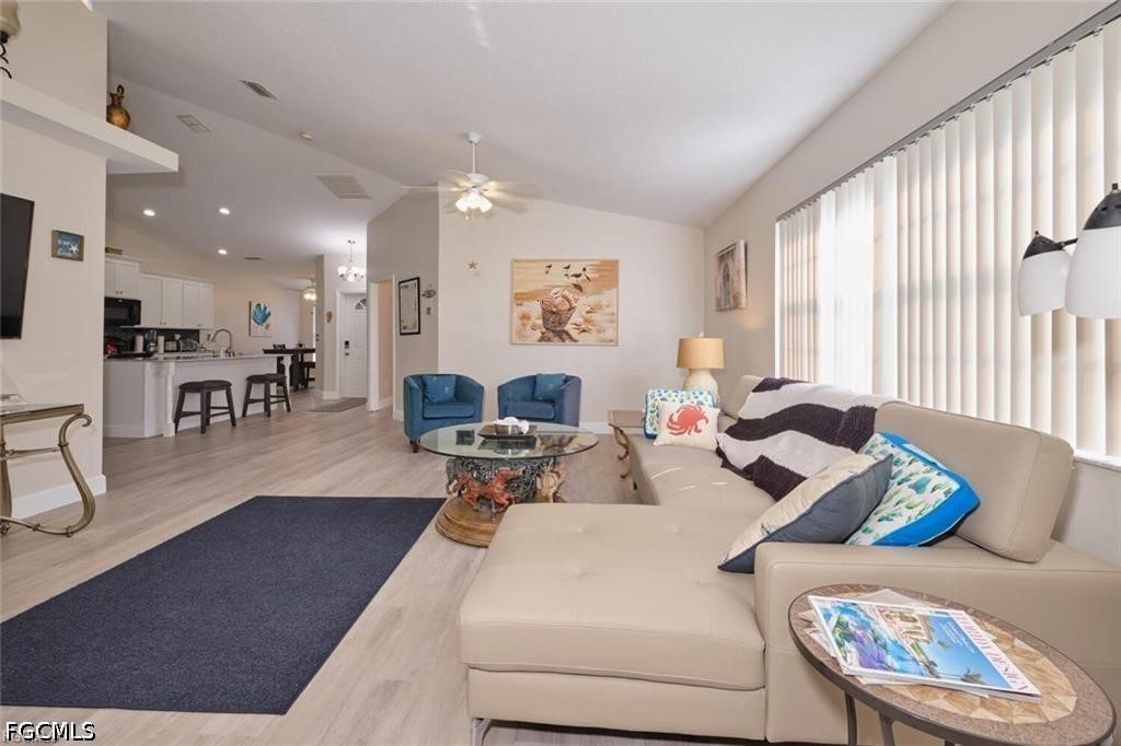 Living room with a cream sectional, blue chairs, and an open kitchen with bar seating.