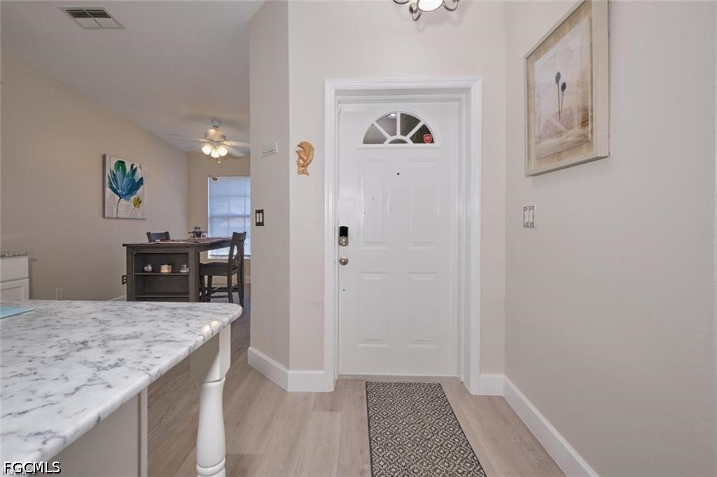 Entryway with a white front door, patterned runner, and marble-look kitchen counter.