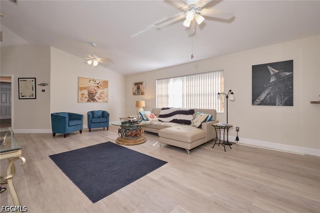 Living room with a cream sectional, blue armchairs, and a large window with vertical blinds.