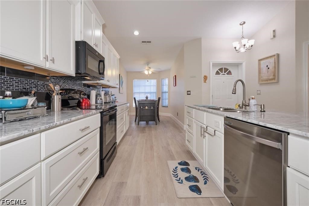 Bright kitchen with white cabinets, stainless steel appliances, and a black tile backsplash.