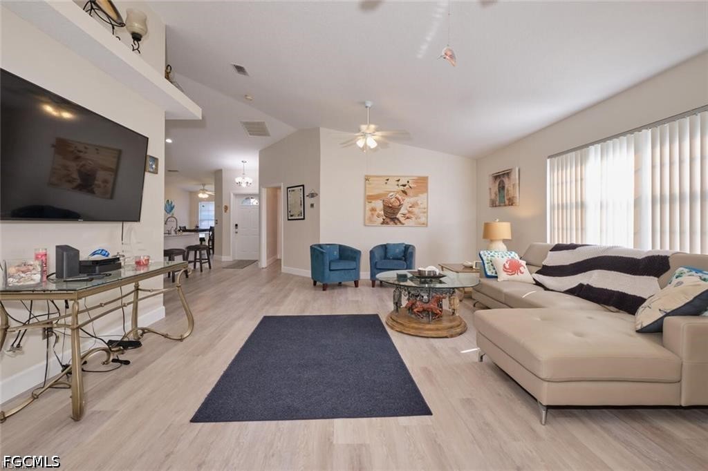 Living room with a beige sectional, blue armchairs, and large television beside a bright window.