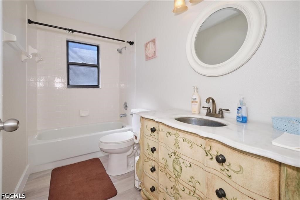 Bathroom with a bathtub, small window, and ornate cream vanity beneath an oval mirror.