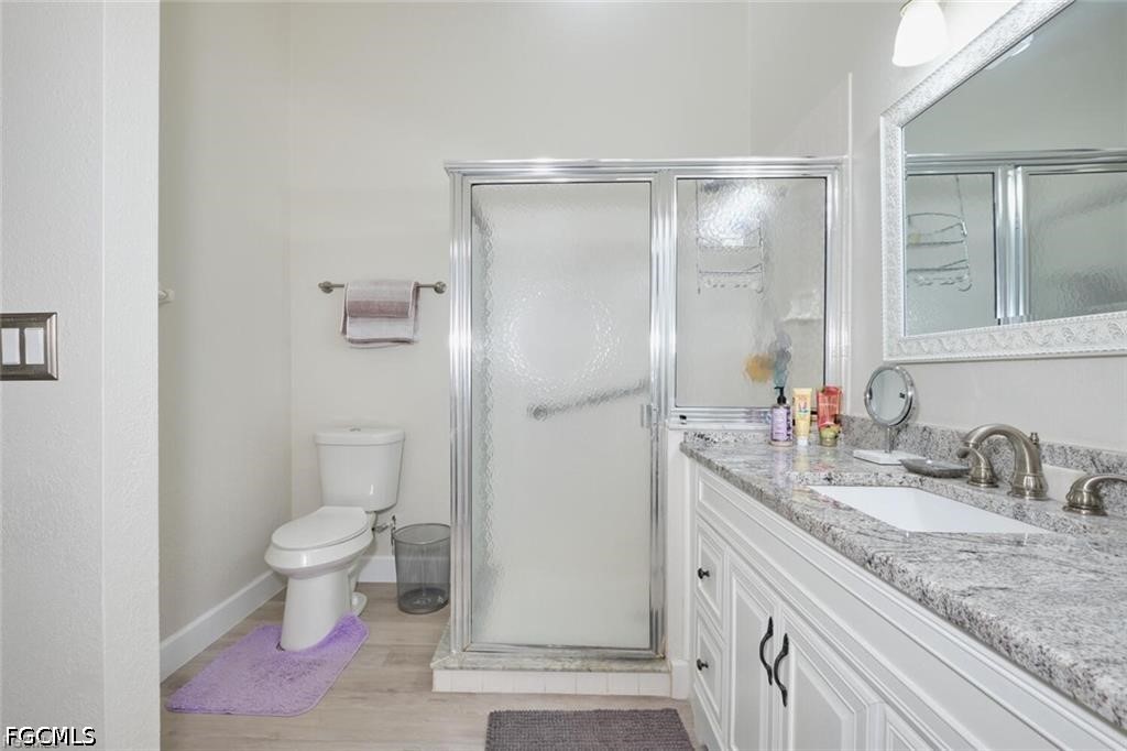 Bathroom with a frosted-glass shower and long double-sink granite vanity.
