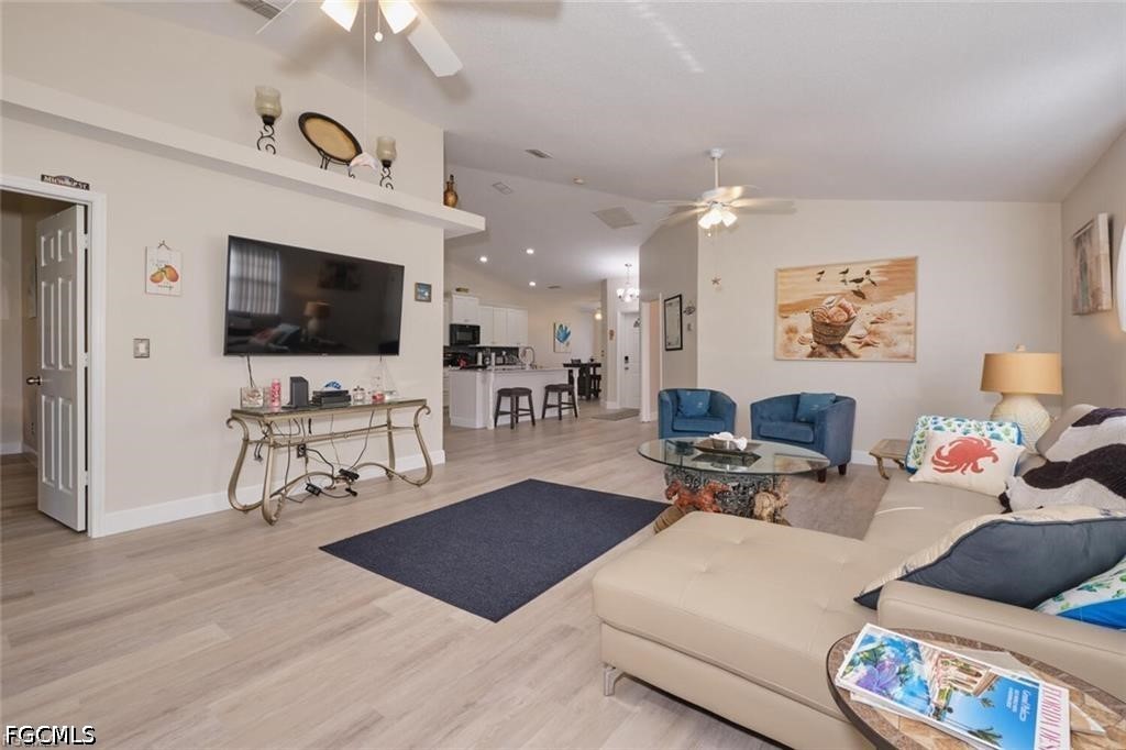 Open-plan living room with a cream sectional, blue armchairs, and kitchen beyond.
