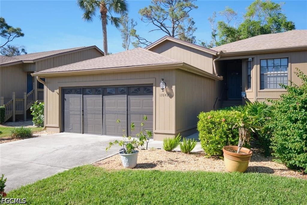 Tan single-story home with a two-car garage, wide driveway, and landscaped front yard.