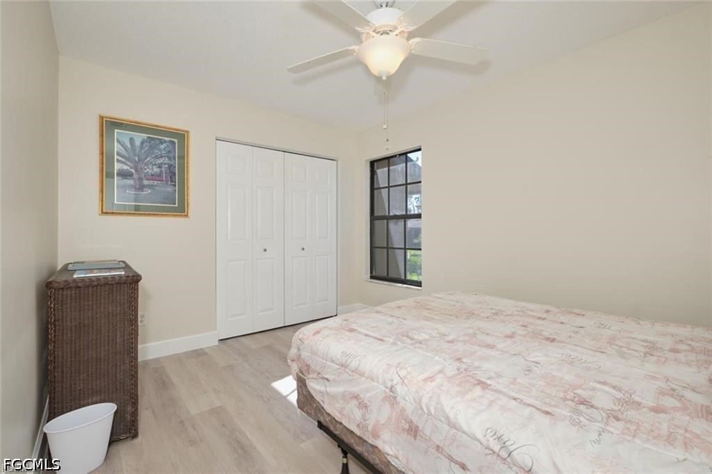 Bedroom with a pale pink patterned bedspread, white closet doors, and a black-framed window.