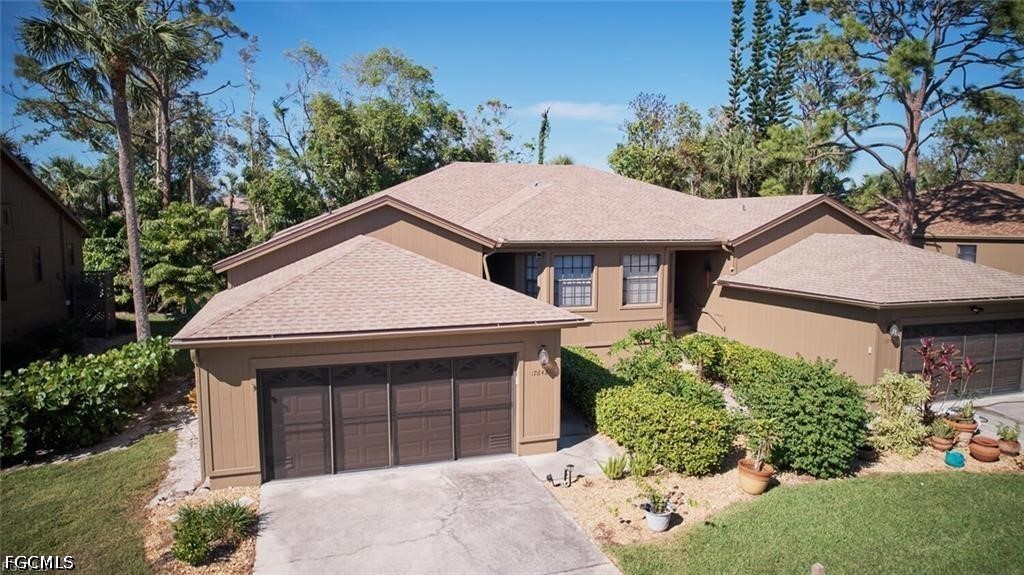 Tan two-story home with multiple garage doors, driveway, and landscaped front yard.