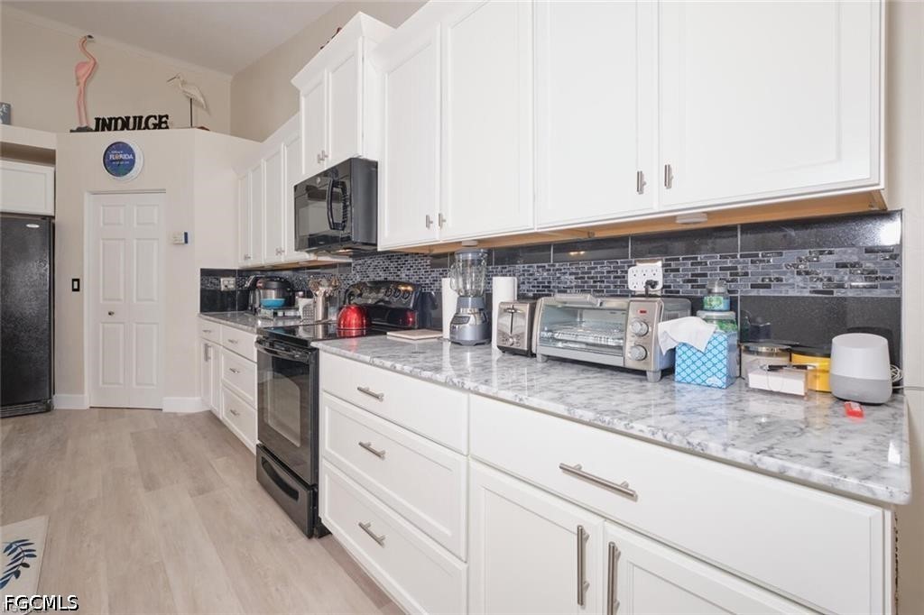 Kitchen with white cabinets, marble-look counters, gray mosaic backsplash, and stainless steel appliances.