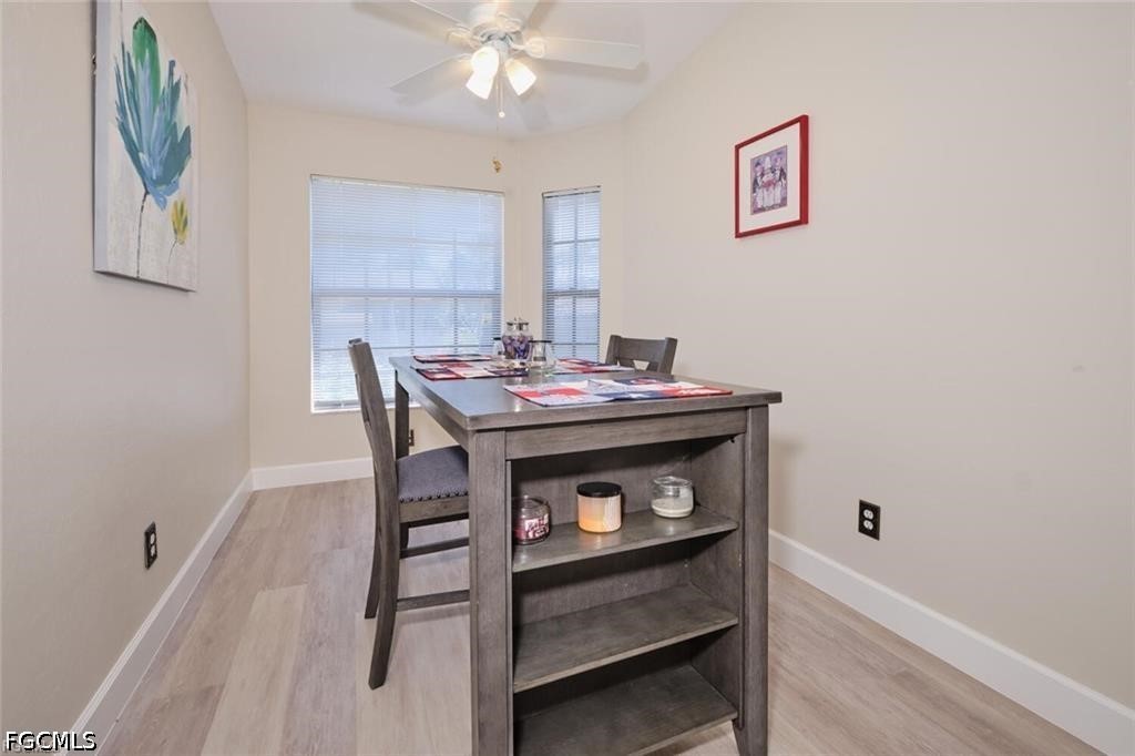 Dining room with a dark gray table, colorful placemats, and two windows with blinds.