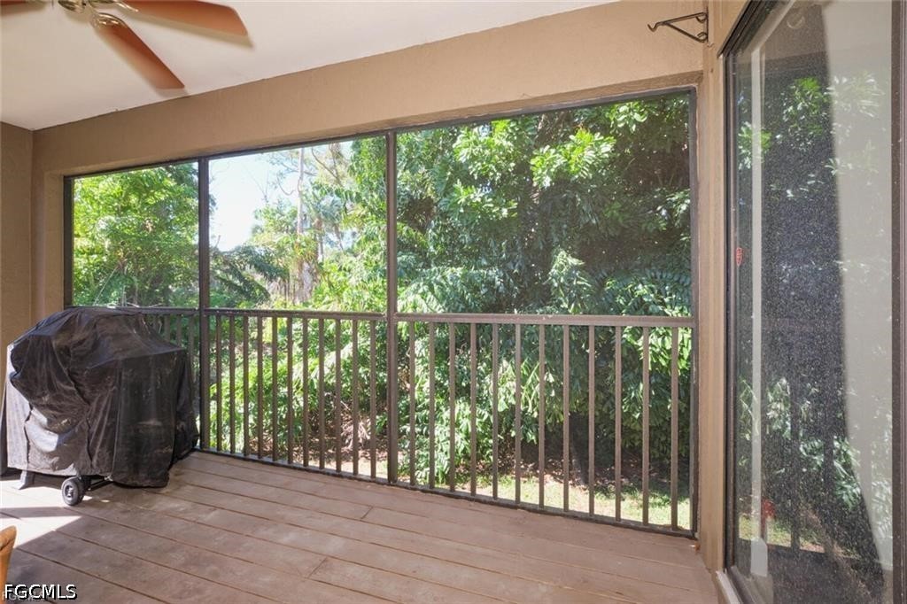 Screened lanai with a covered grill and leafy vegetation beyond the railing.