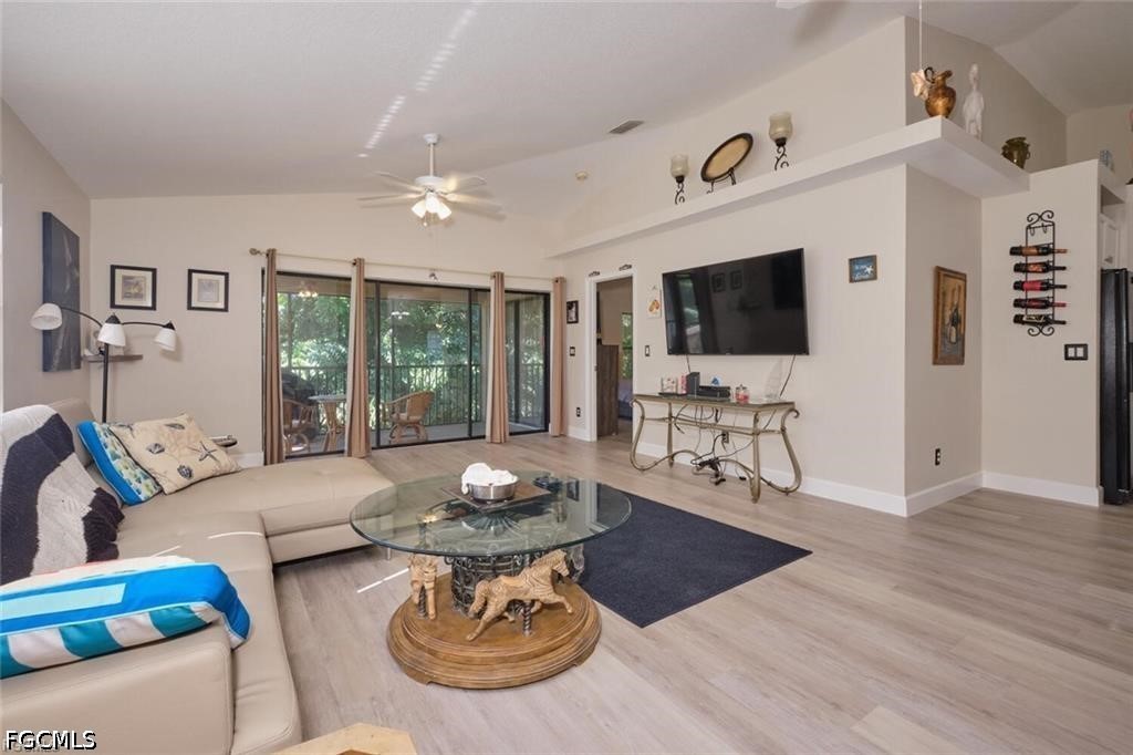 Living room with a cream sectional, glass coffee table, and sliding doors to a tree-lined patio.