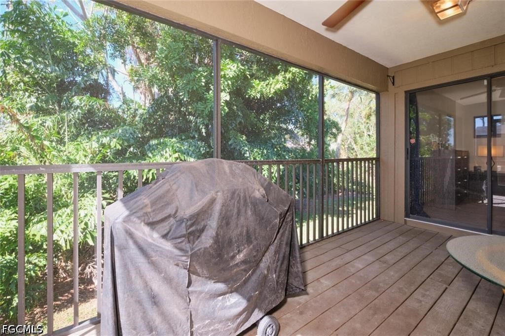 Screened lanai with a covered grill and dense green foliage beyond the railing.