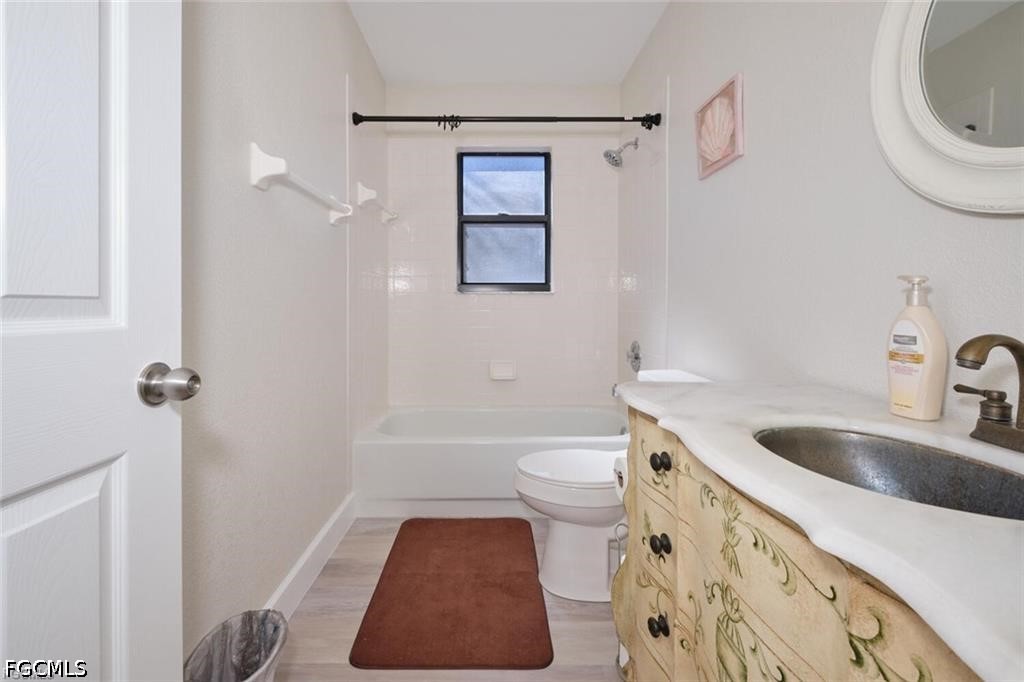 Bathroom with a bathtub beneath a window and a decorative cream vanity with a dark sink.