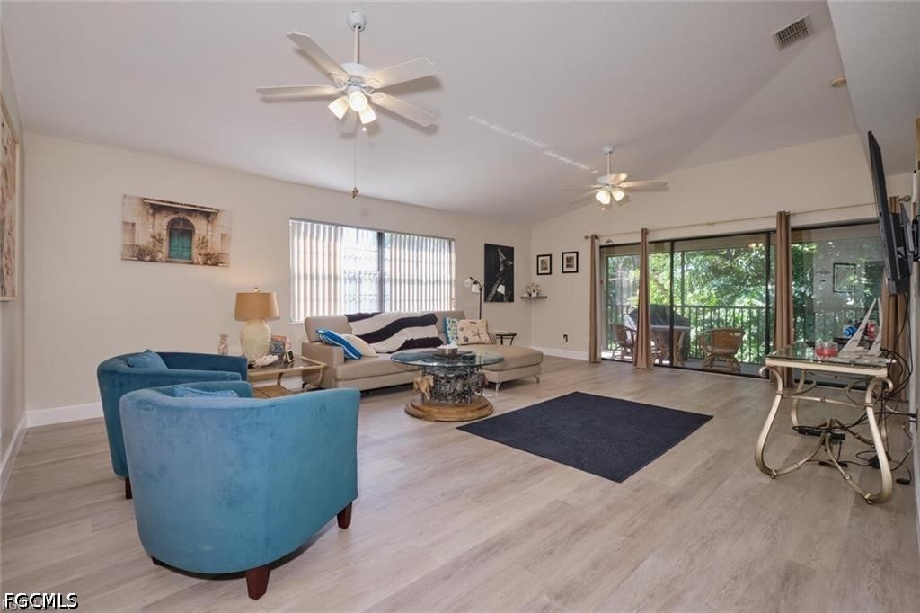 Living room with blue armchairs, beige sectional, ceiling fans, and sliding doors to a screened outdoor area.