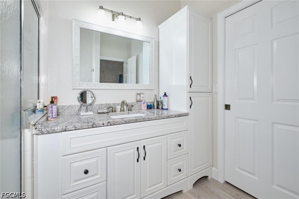 Bathroom vanity with a speckled stone countertop, large mirror, and glass shower enclosure.