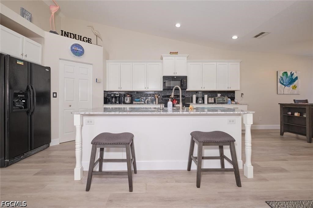 Kitchen with a large white island, gray countertop, and two upholstered stools.