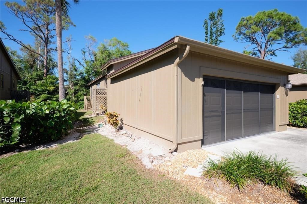 Beige garage with dark multi-panel doors beside a landscaped lawn.